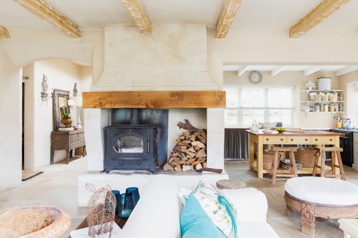 A farmhouse-style home interior with an antique wood stove sitting next to a modernized keeping room and dining room.