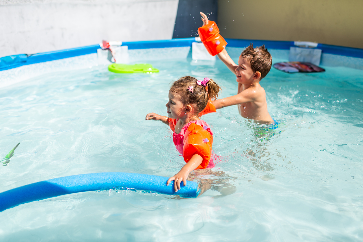 A boy and a girl are playing in swimming pool, excited because summer is here.