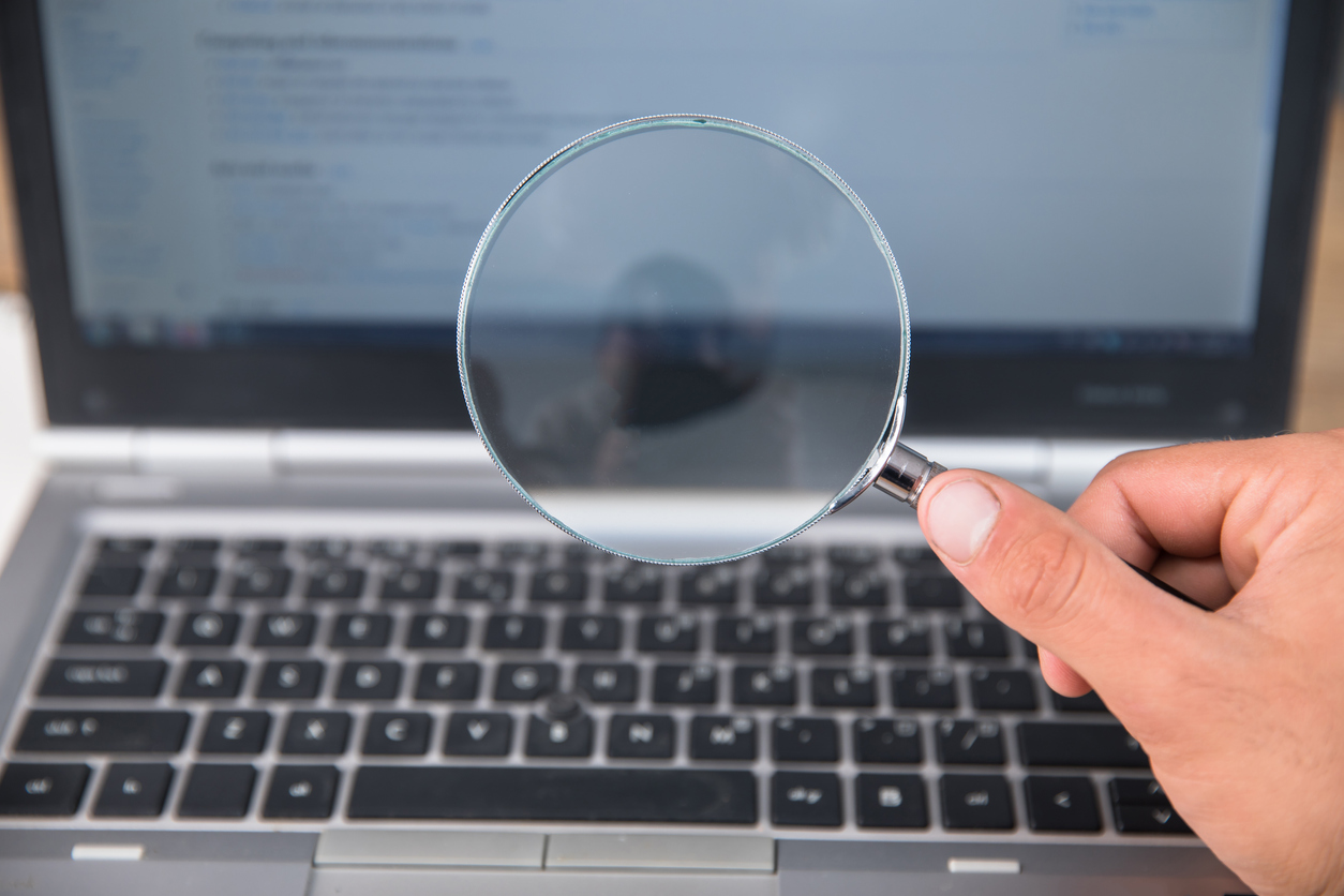 business man holding magnifier with laptop