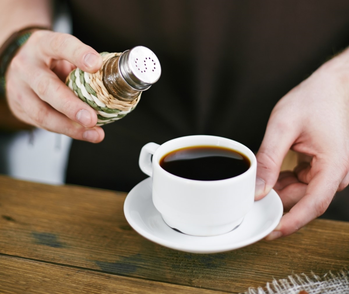 Adding salt to coffee cup.