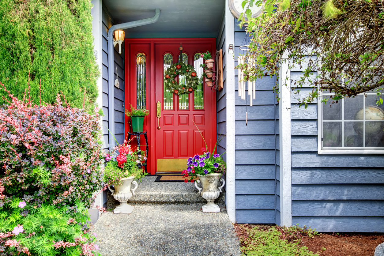 Blue modern house with red door and paved walkway.