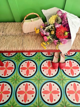 Green shiplap walls with natural bench and colorful green and pink tile on the floor.