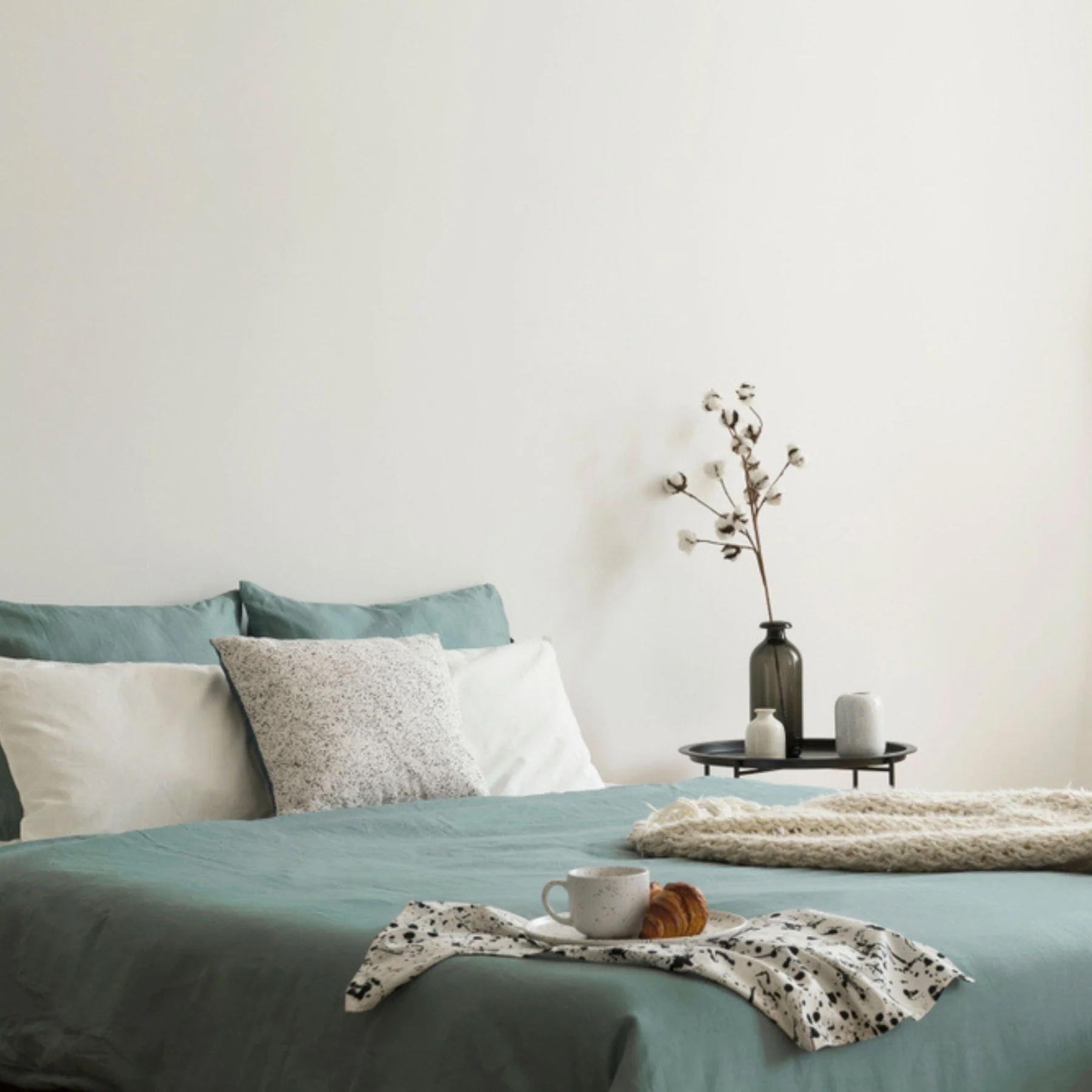 Bedroom with modern teal bedding and walls painted in Historic White by Dunn Edwards.