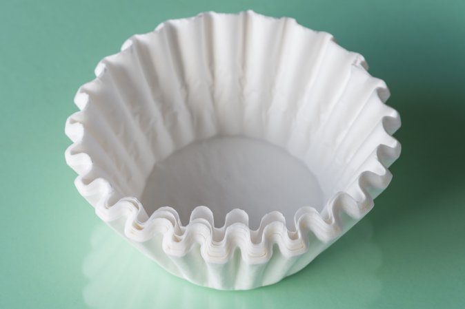 a stack of unused white coffee filters on a light green table.