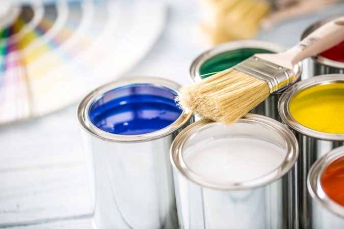 Paint brush laying on top of opened paint cans.