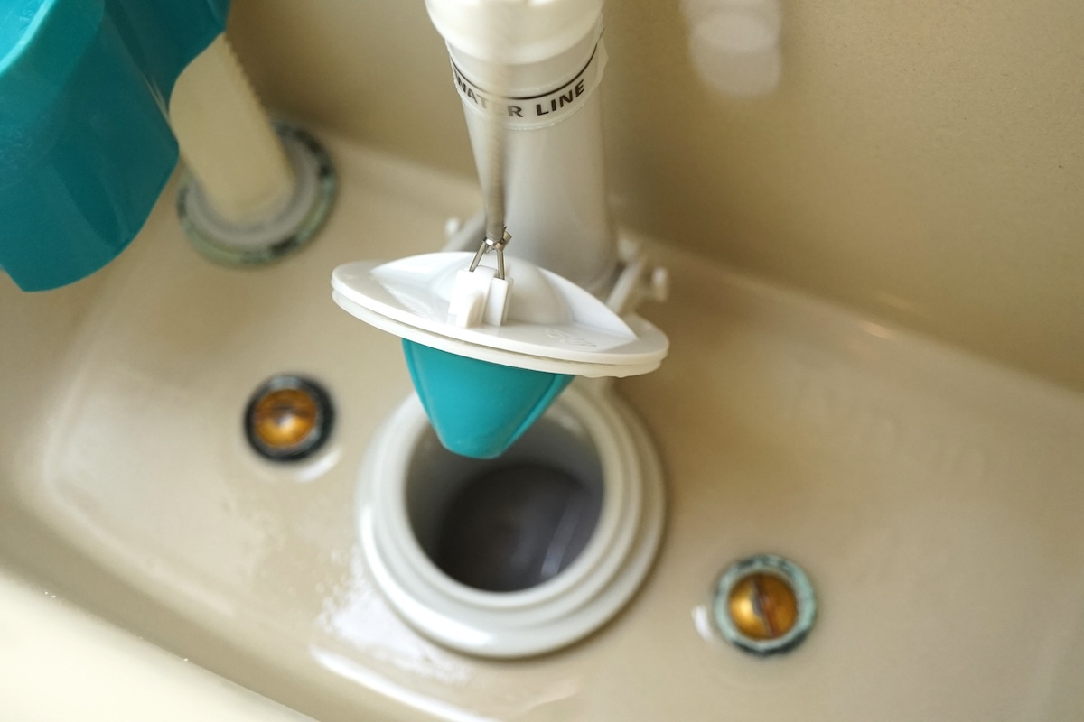 Inside a modern toilet tank showing a flush valve opening.