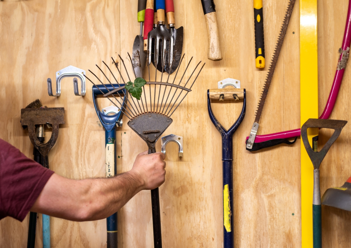 Male arm putting away garden rake.