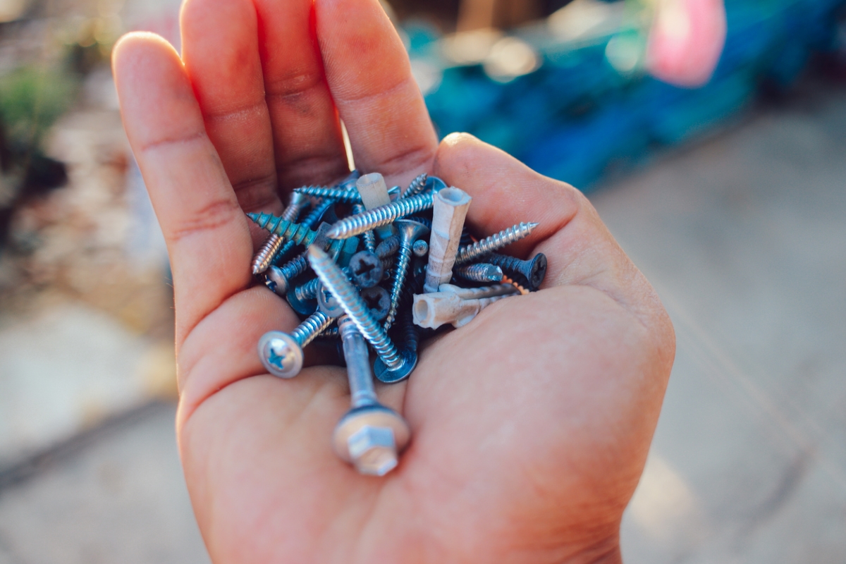 Hand holding various small screws.