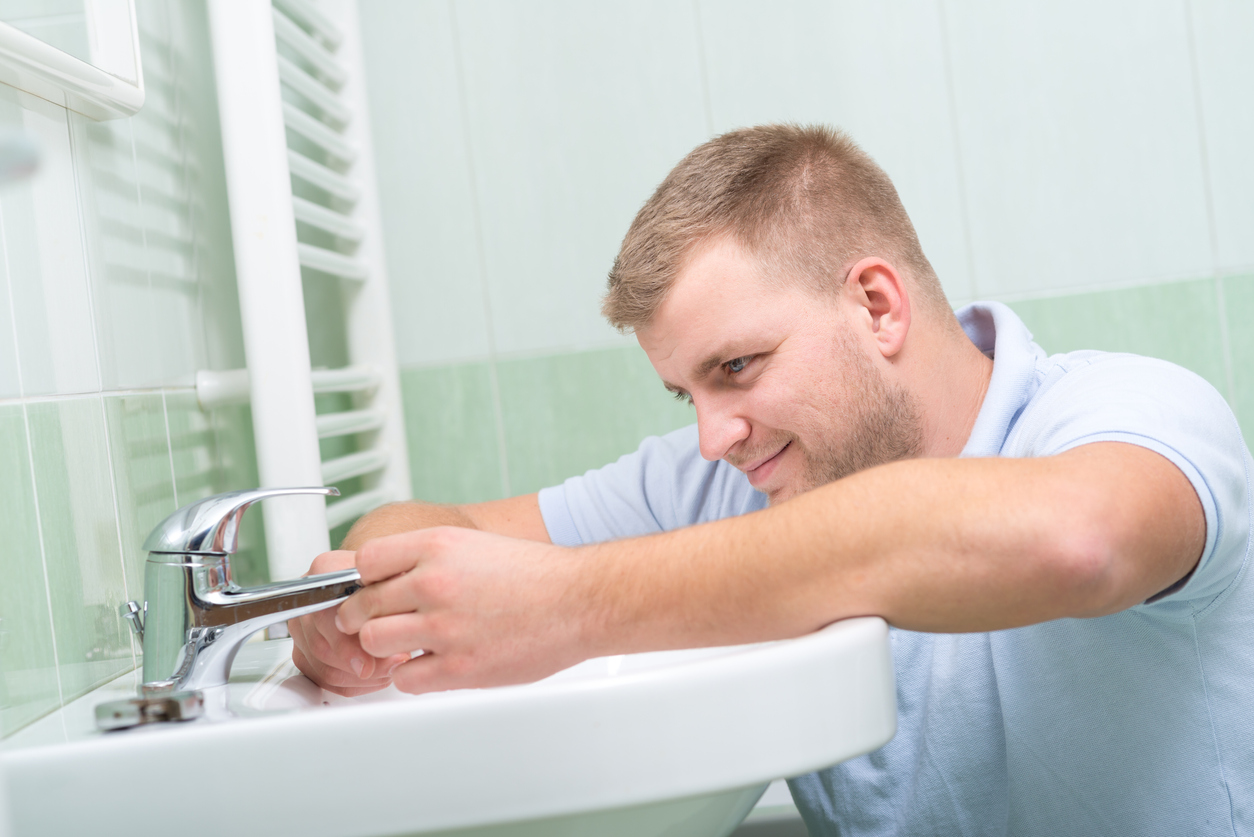 A-person-installs-a-crome-faucet-in-a-bathroom-sink.