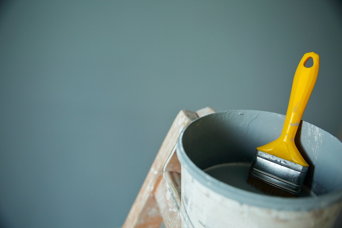 A can of green paint on a ladder reading to touch up paint on walls.