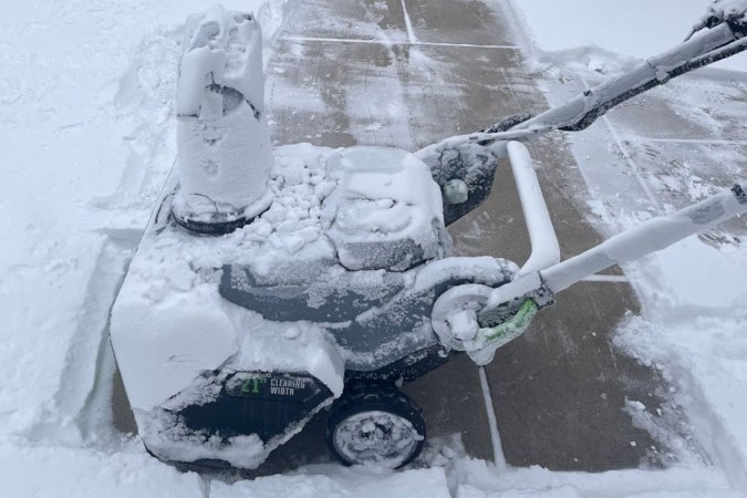 The Ego Lightweight Snow Blower covered in snow at the end of a cleared path.