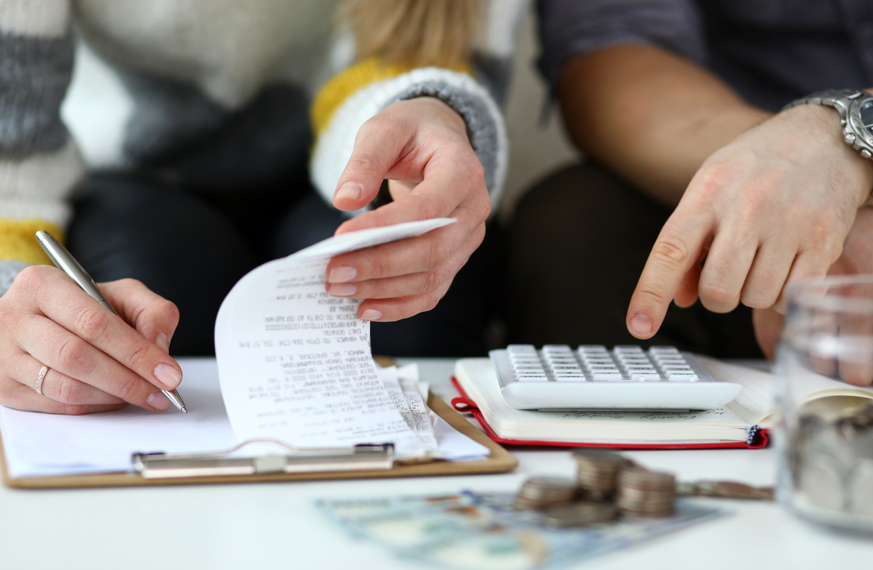 A close up of the hands of two people going over documents and using a calculator. 