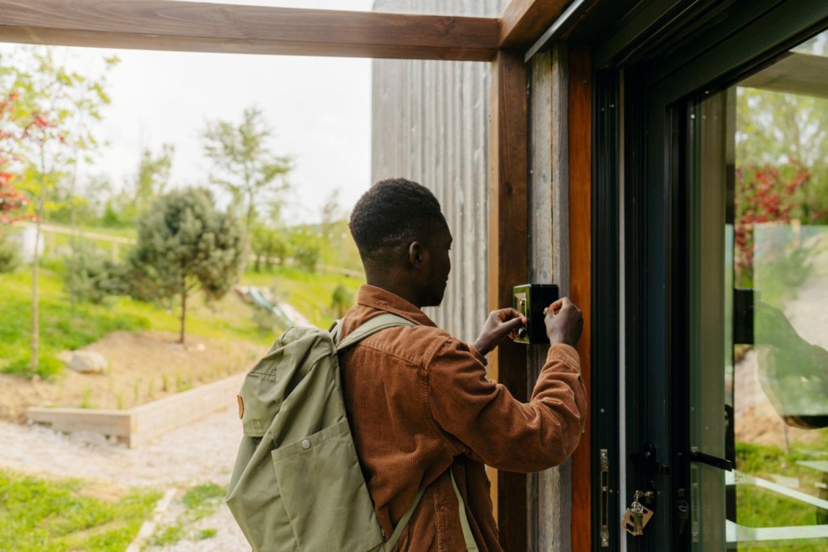 A person gets a key form a box before walking through the front door of a house. 