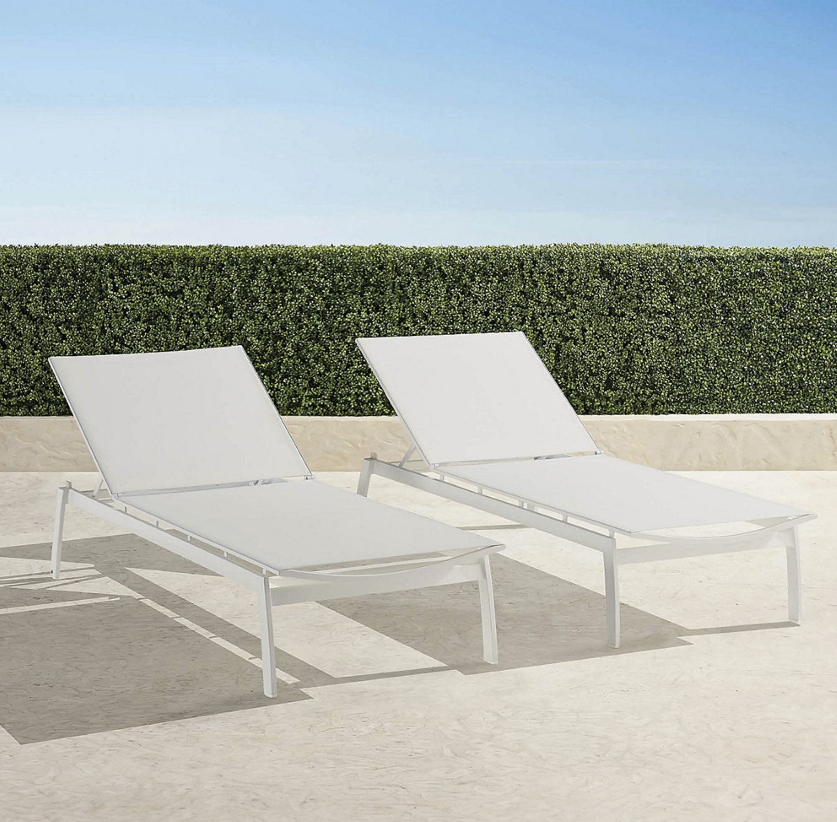 Two white aluminum chaises on patio.