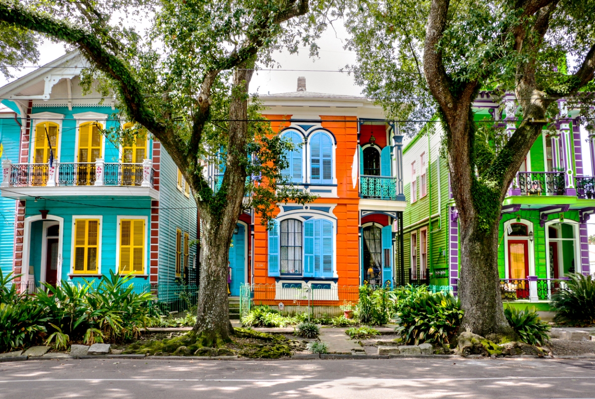 Colorful homes with large trees in front.