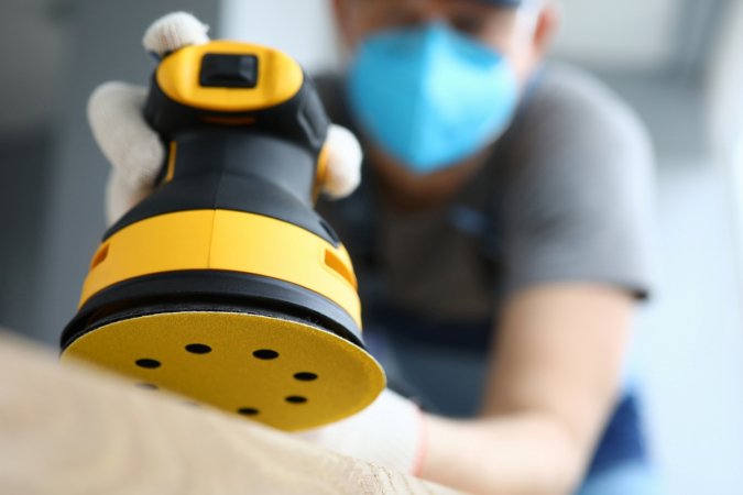 Person holding yellow disc sander.