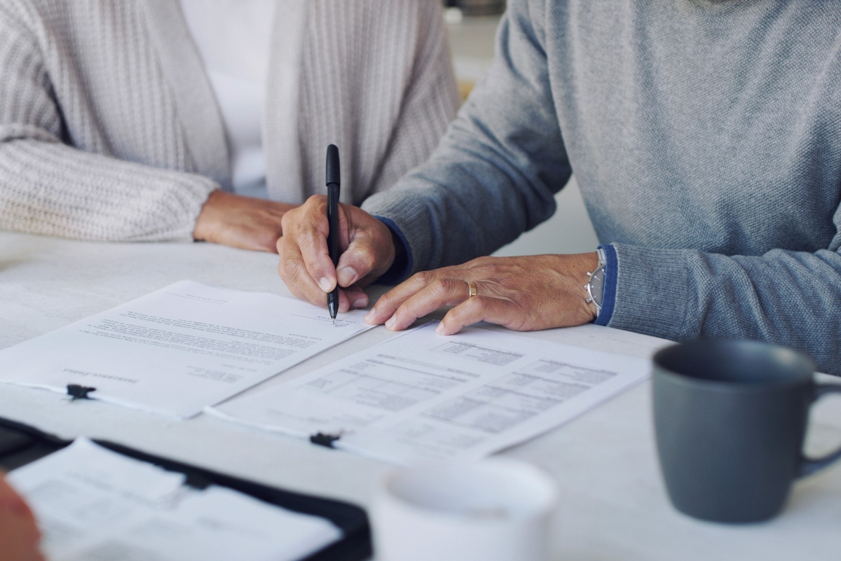 Two people signing contract papers.