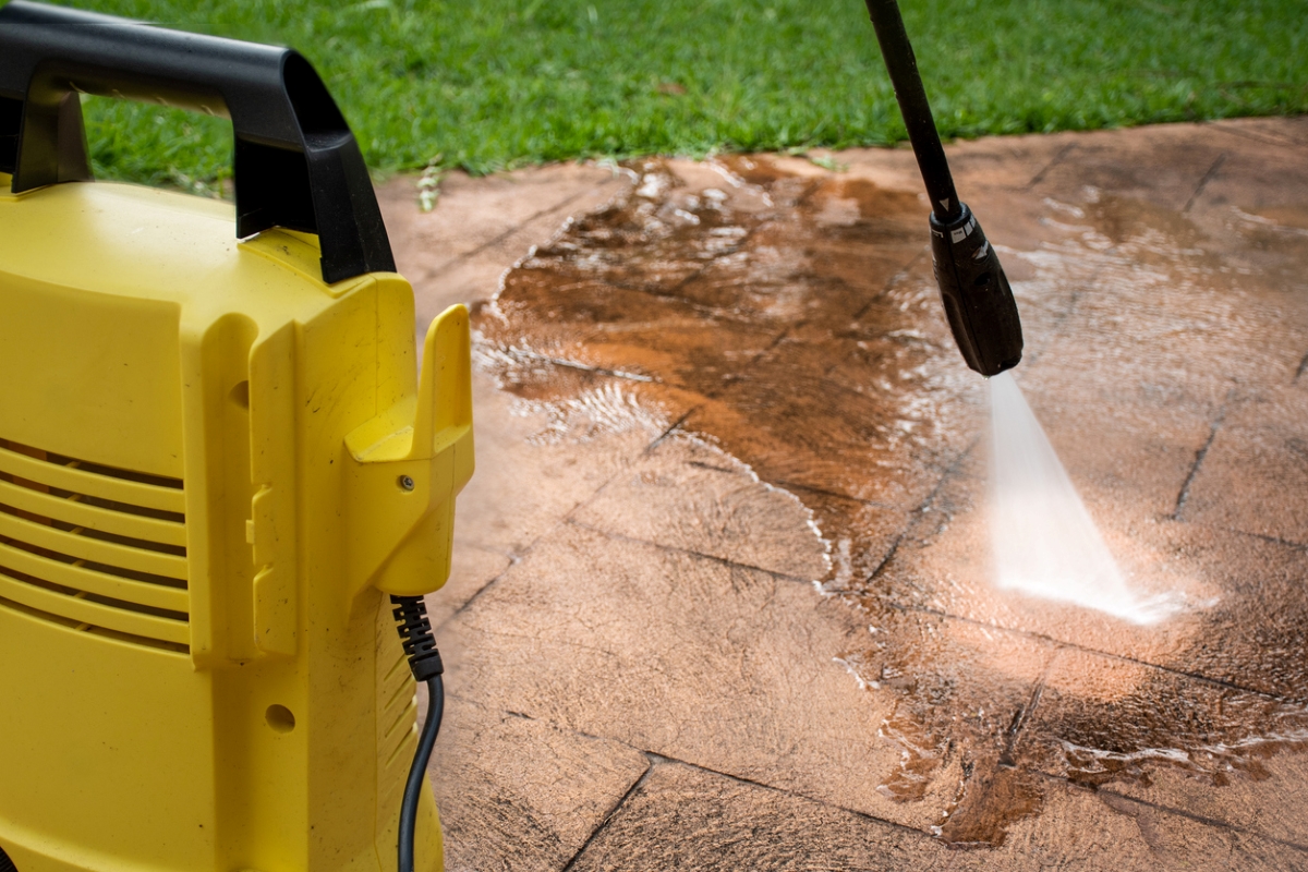 Backyard pavers being cleaned by pressure washer.