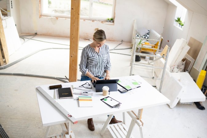 A person standing at a table documenting remodeling expenses for tax credits and deductions.