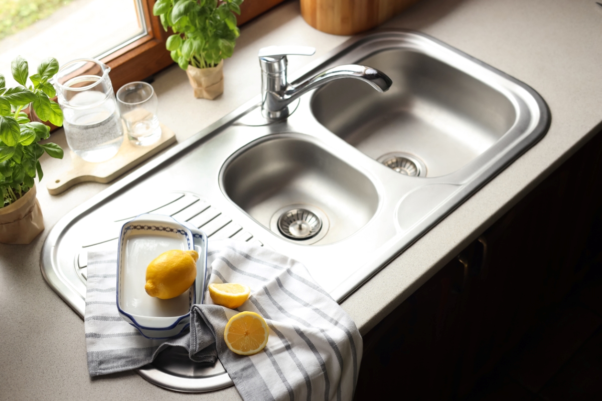 Fresh lemons next to silver kitchen sink.