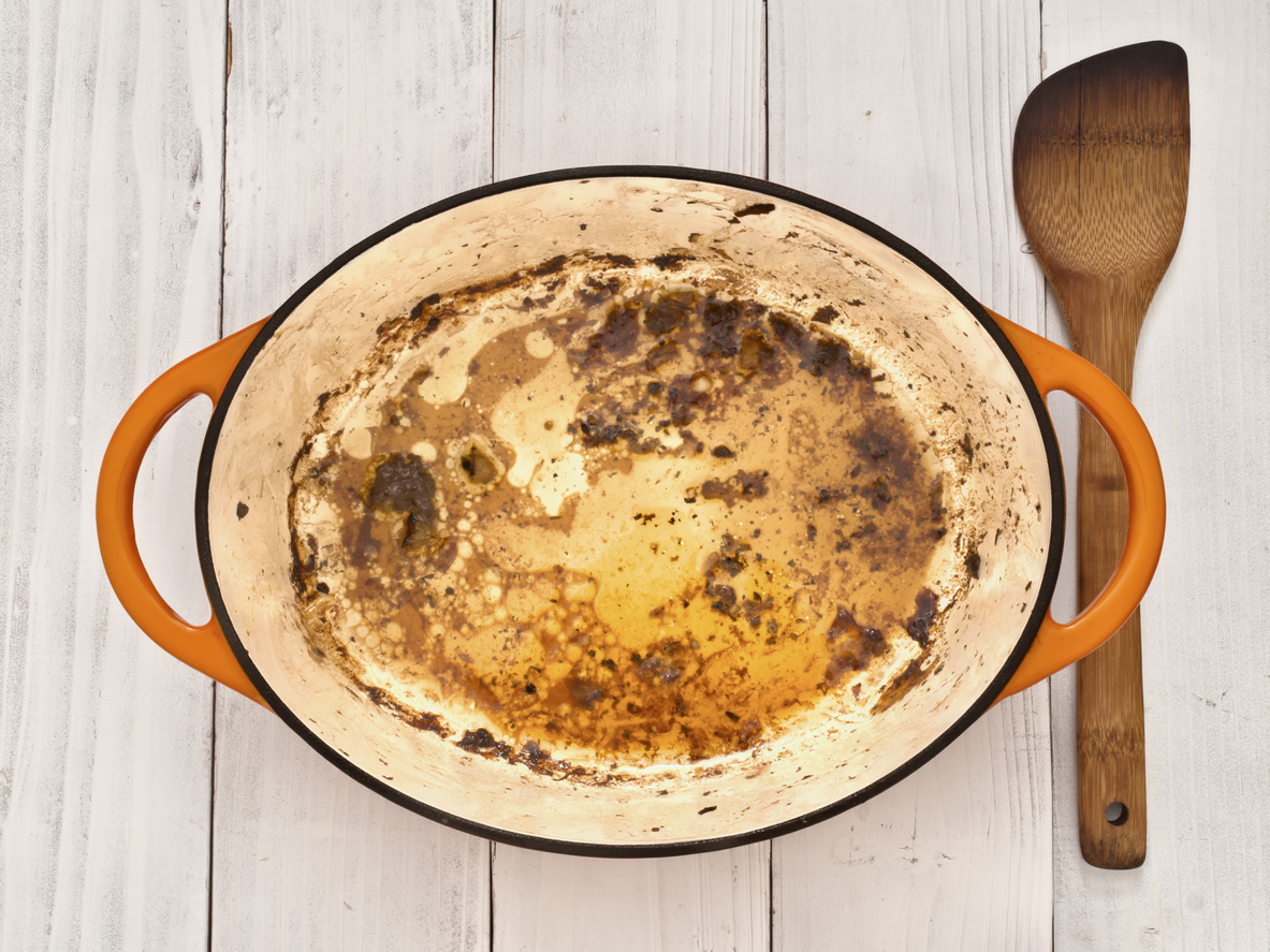 Orange enamel pot stained and discolored with food.