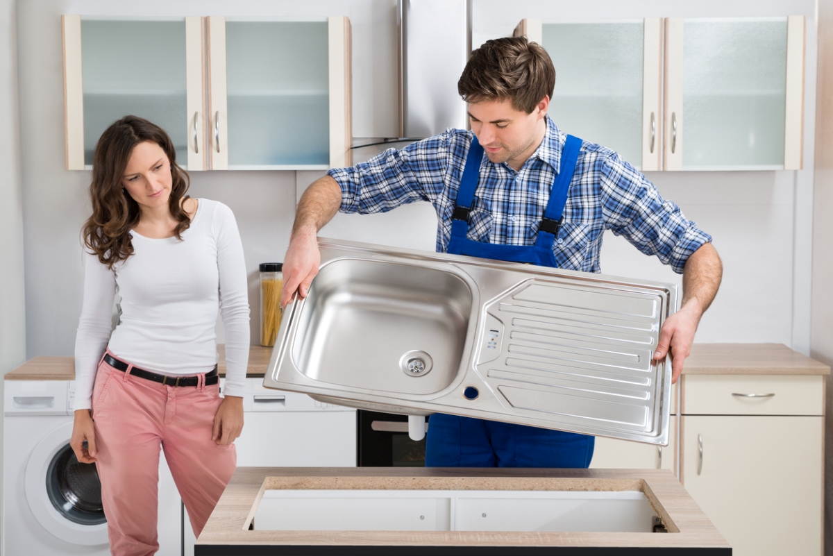 Woman looking at handyman removing sink.