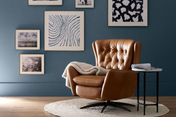 The Best Swivel Chair on a small rug in front of a blue wall decorated with art.