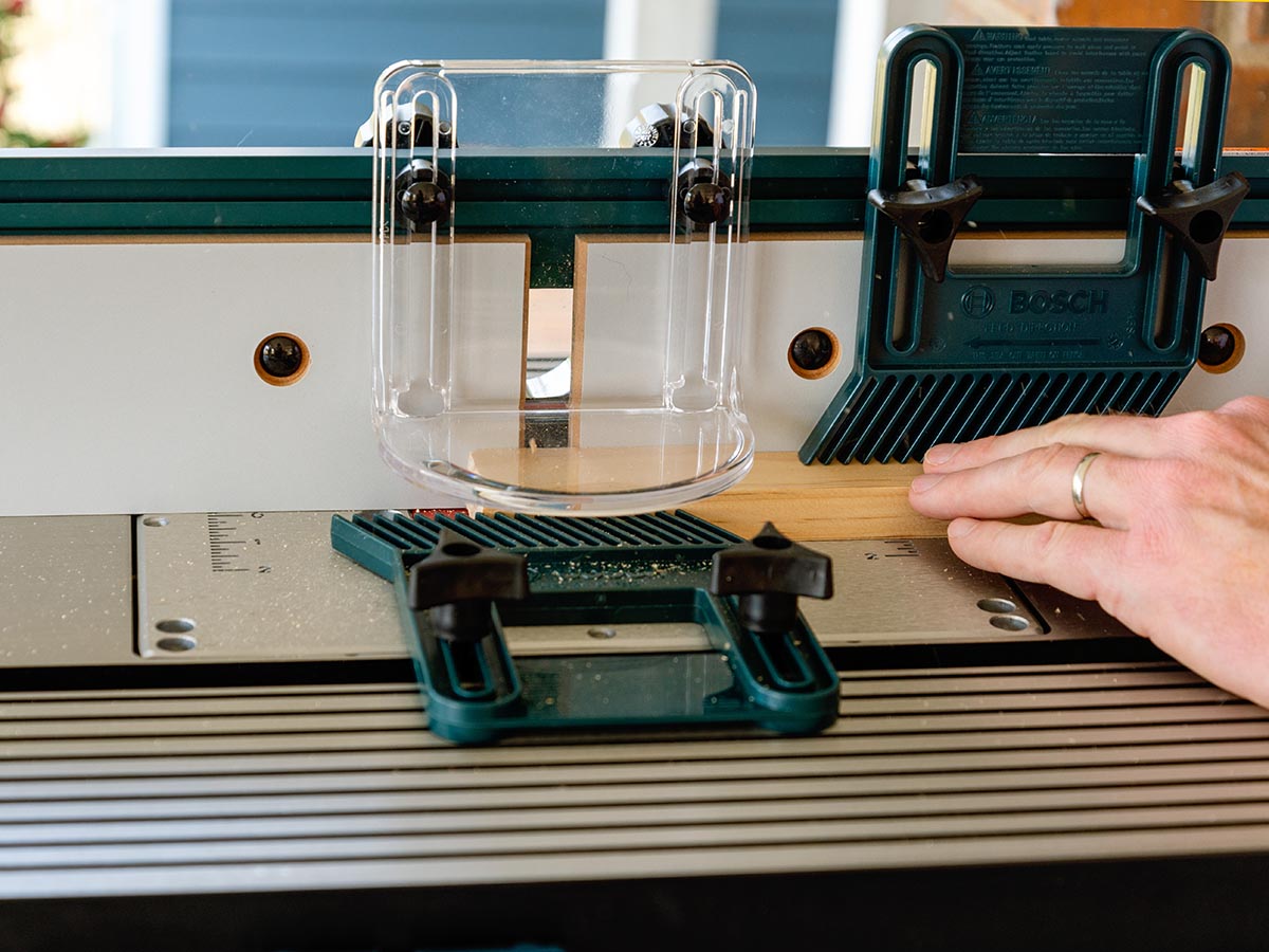 A person clamping a piece of wood onto the Bosch Benchtop Router Table during testing.