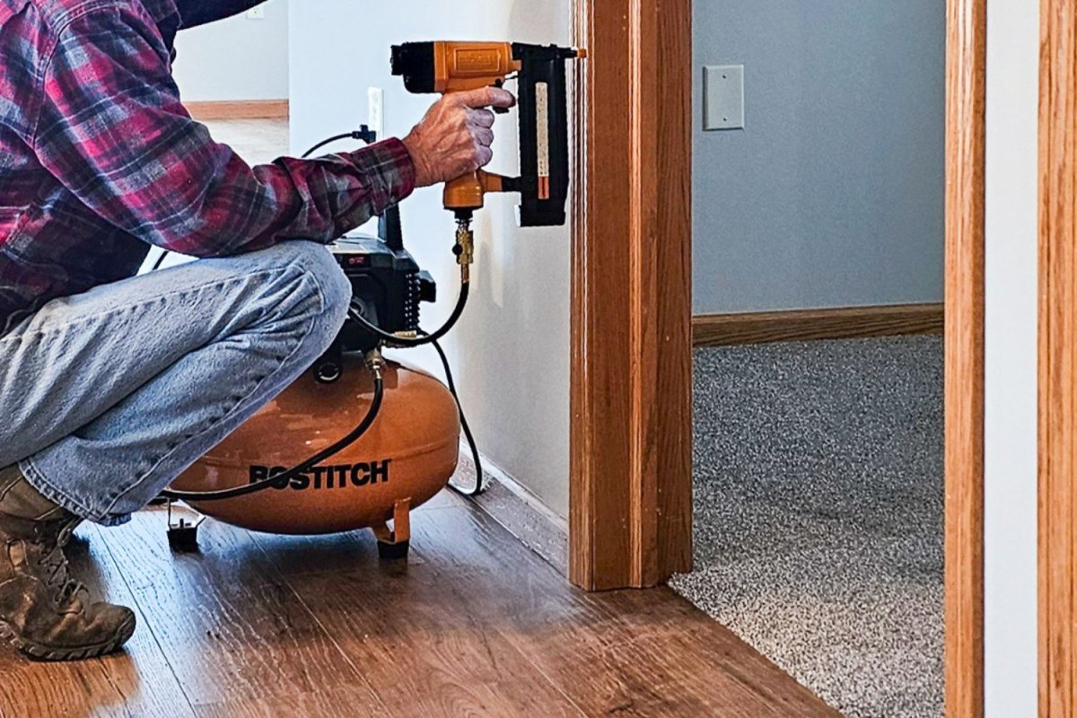 A person using a Bostitch finish nailer attached to the Bostitch Air Compressor during testing.