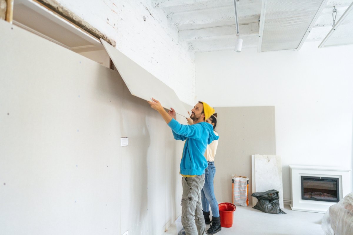 Two people finish construction on a wall. 