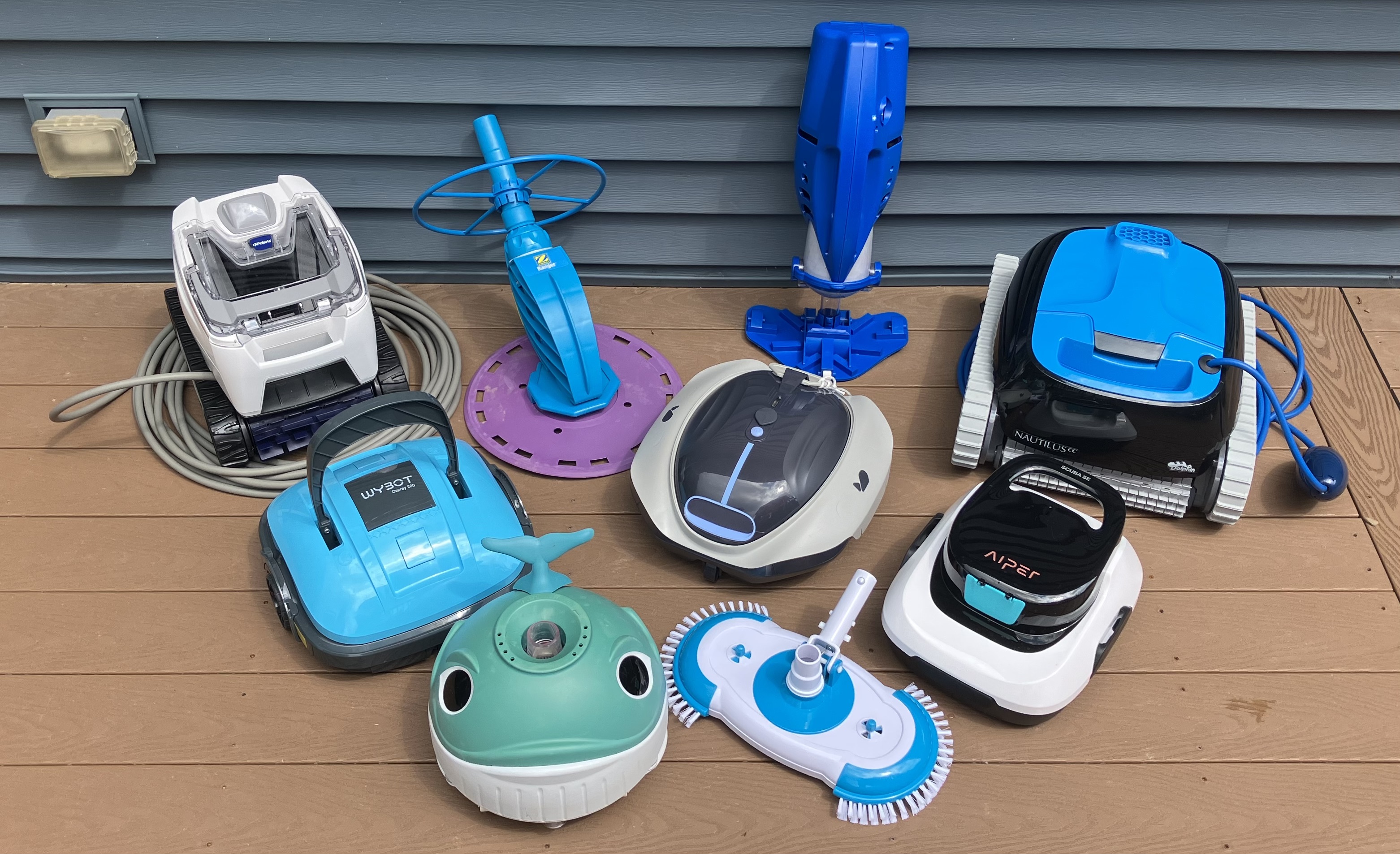 Nine of the pool vacuums we tested in above-ground pools, grouped together on a pool deck