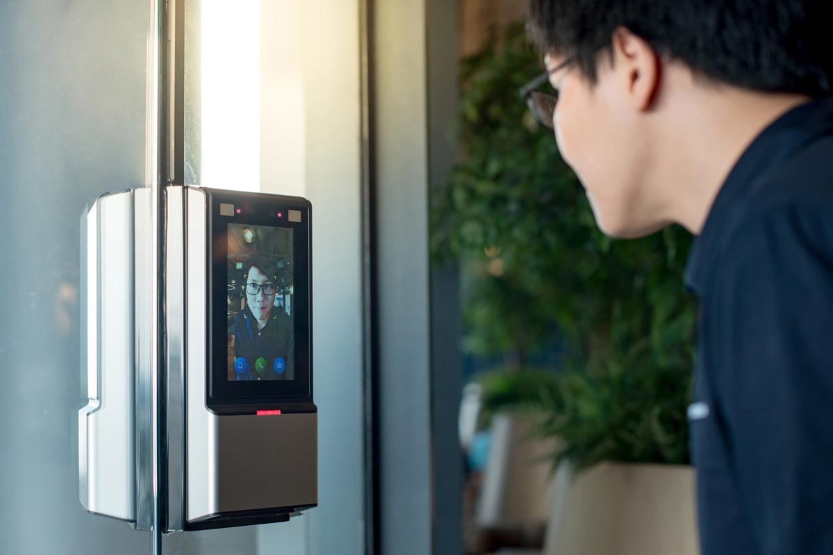 A person looks closely at a video doorbell. 