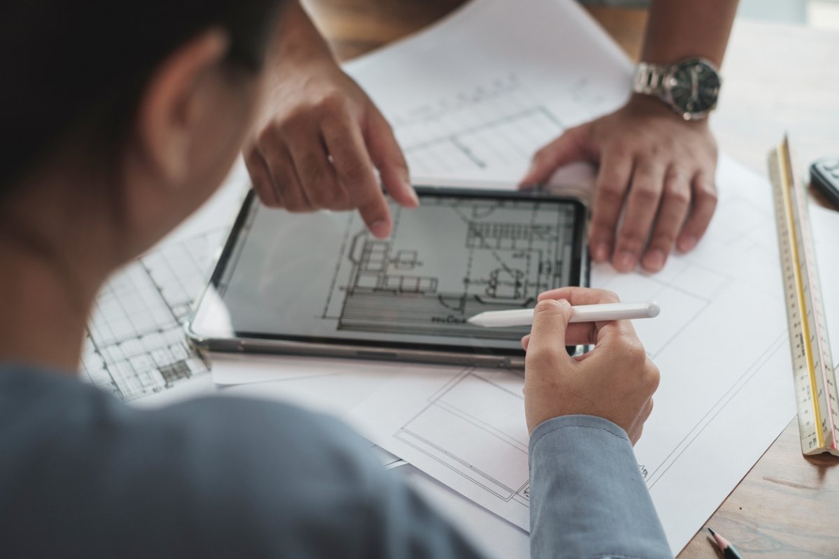 Two people discuss architecture plans shown on a tablet. 