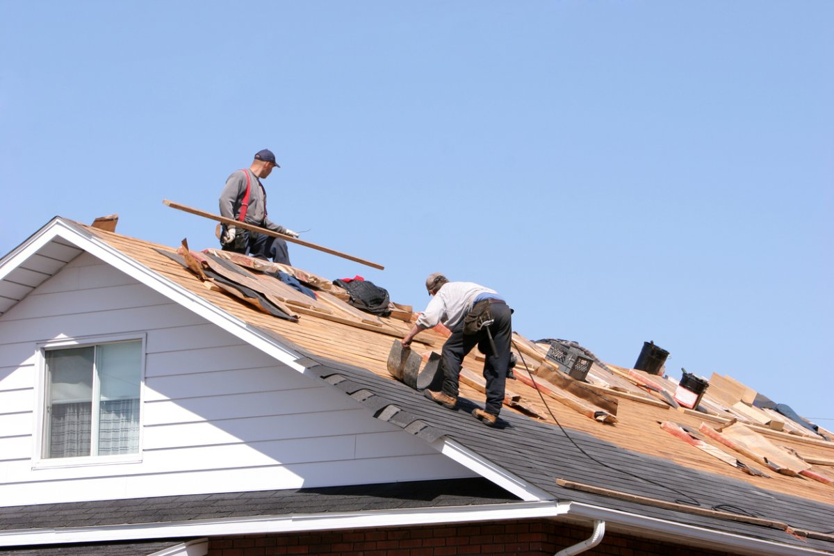 Workers are installing a new roof on a clear day.