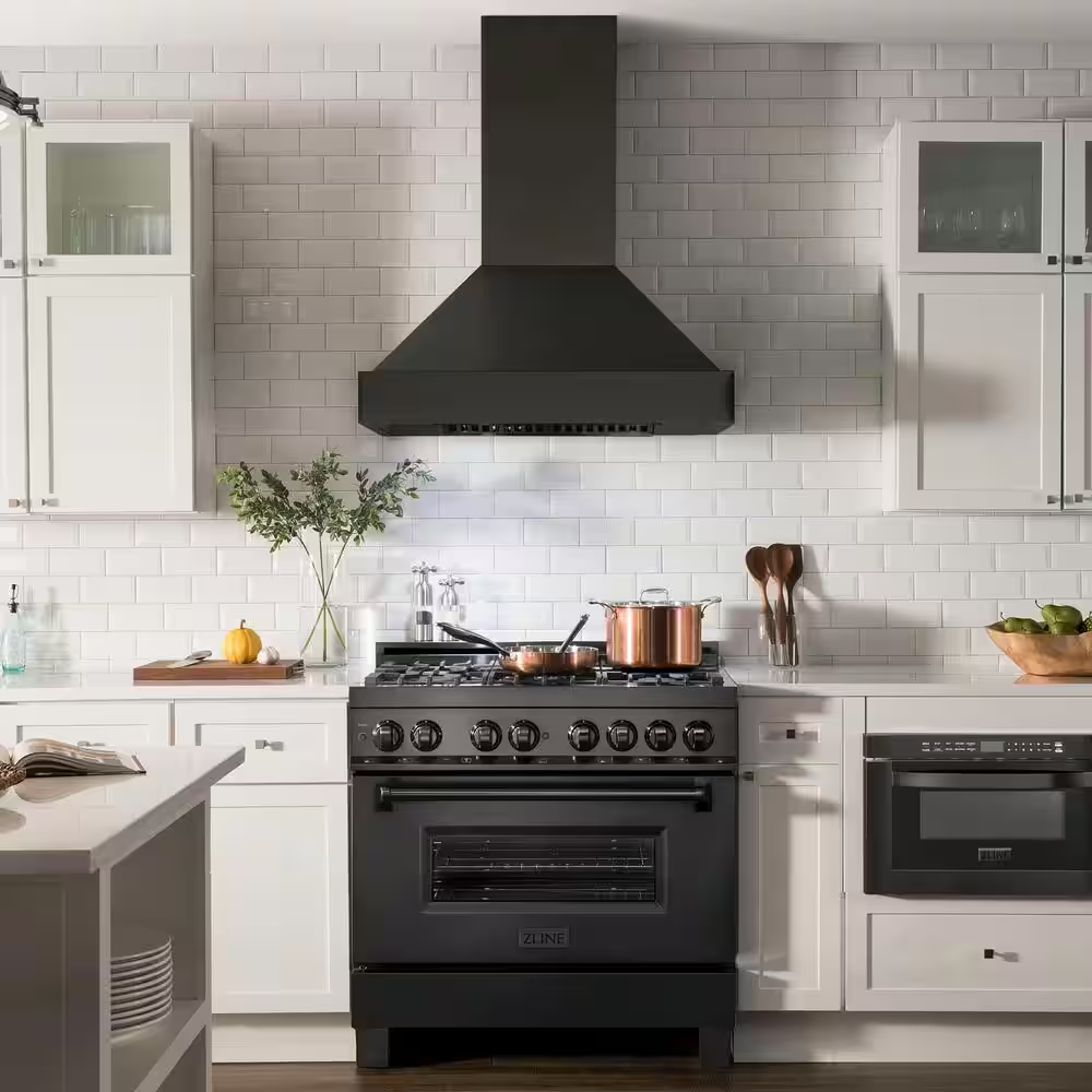 A matte black steel range hood in a white kitchen with copper decor.