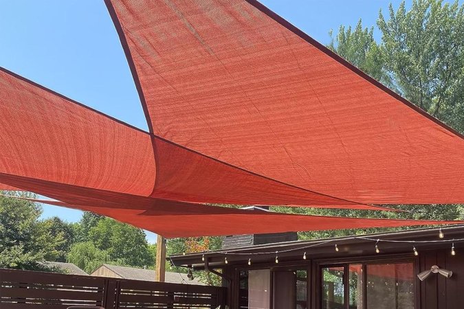  The Love Story Permeable Triangle Shade Sail with a house behind it.