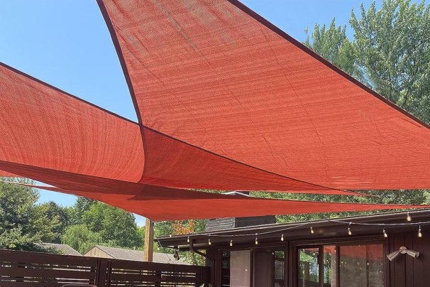 The Love Story Permeable Triangle Shade Sail with a house behind it.