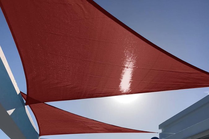  The Sunny Guard Triangle Sun Shade Sail with blue sky behind it.