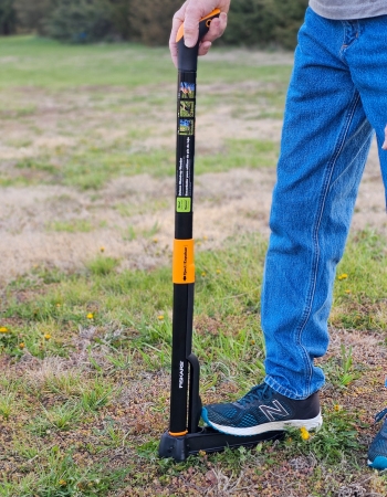 A person pushing the Fiskars Stand-Up Weed Puller into the ground during testing.