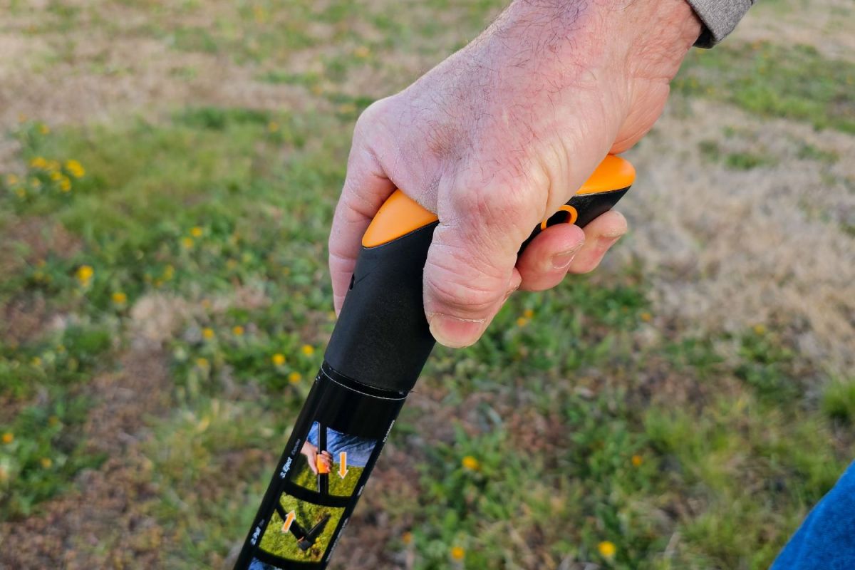 A person's hand on the handle of the Fiskars Stand-Up Weed Puller during testing.