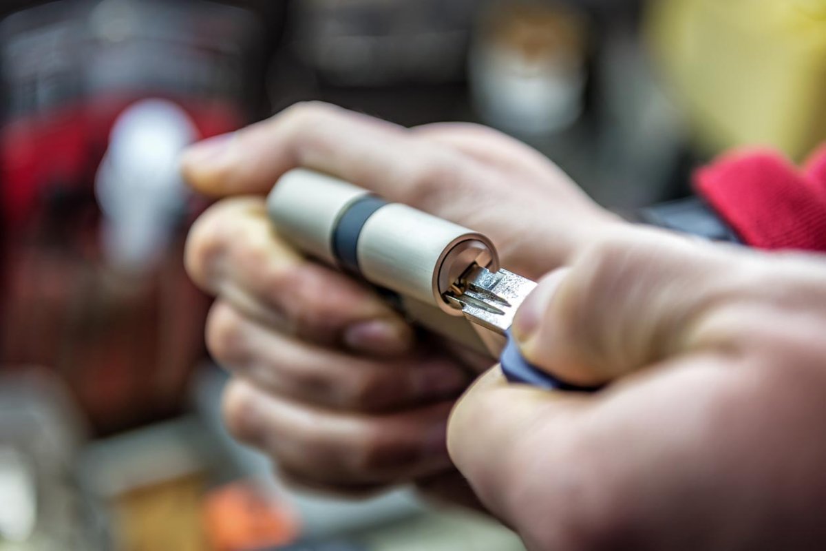 A close up of a person's hands testing a door lock with a key.