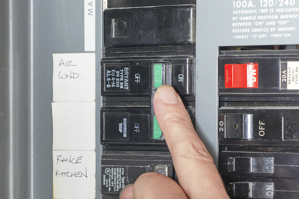 Person touches the circuit breaker switch labeled "air cond."