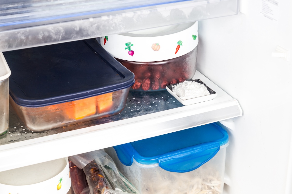 Fridge full of glass and plastic containers with deodorizer a small dish.