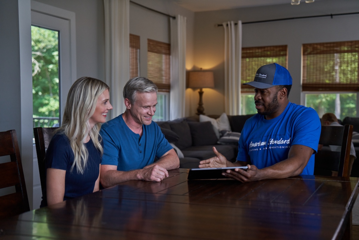 Homeowners talking to an American Standard HVAC expert about installing a heat pump for their home.