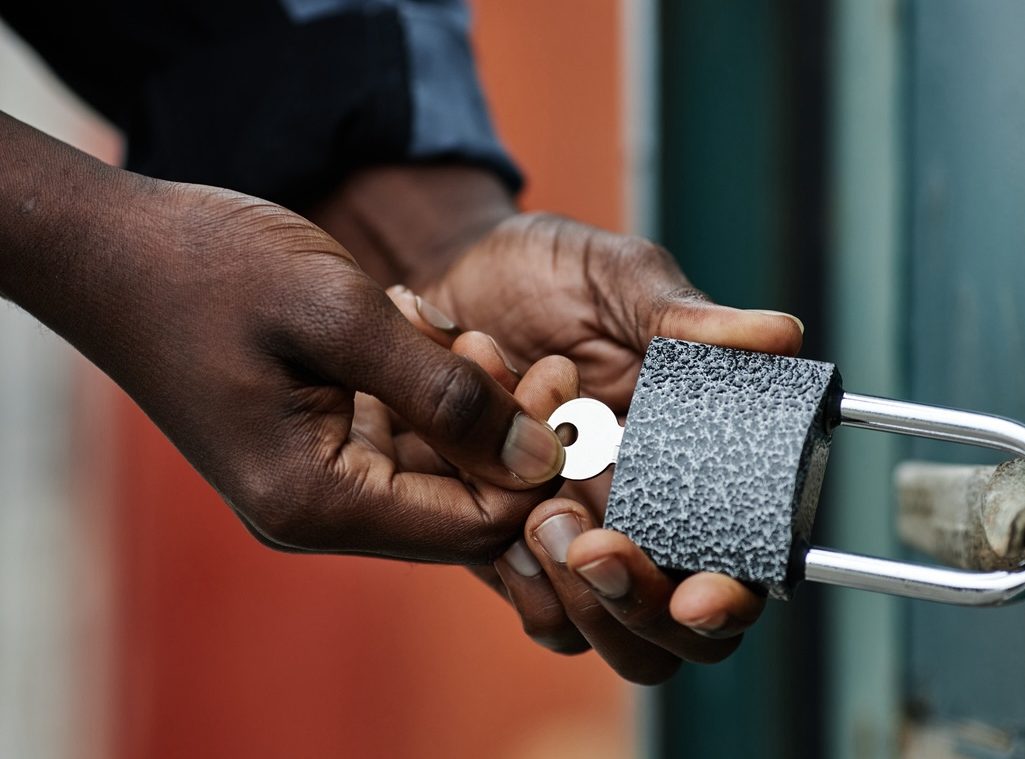 A person using a padlock to lock a garage door.