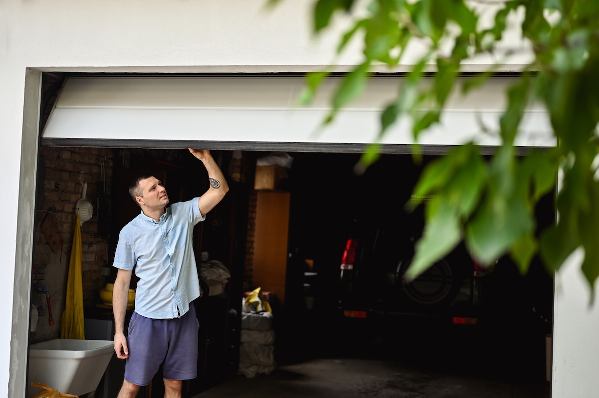 A person closing a garage door attached to his house.