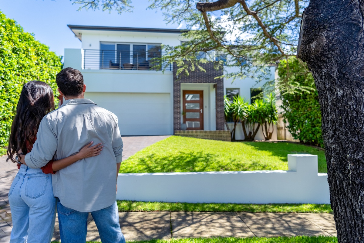 A young couple looking at a nice house in a nice neighborhood considering buying a home.