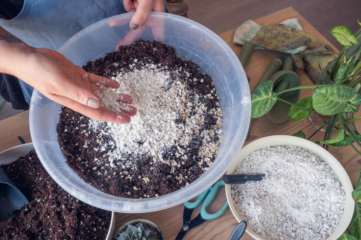 Person mixing potting mix with diatomaceous earth in a plant pot.