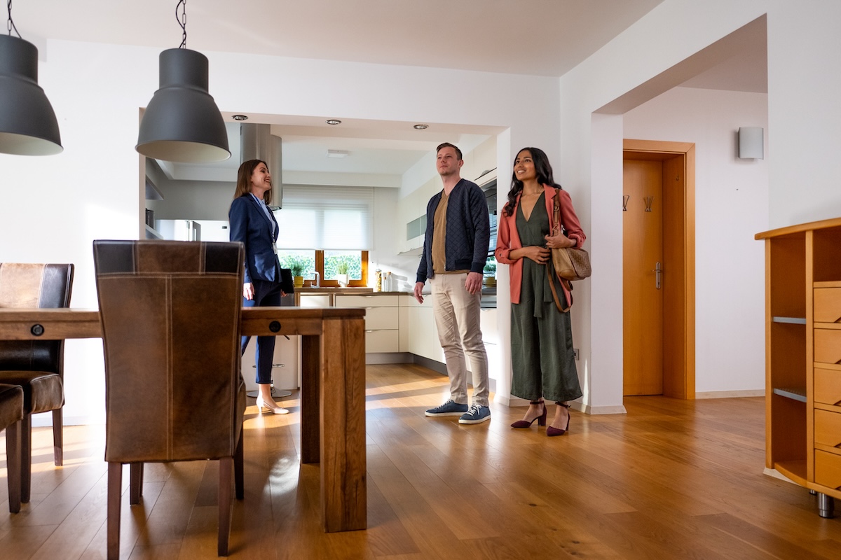 Real estate agent shows young couple an open house in the dining area.