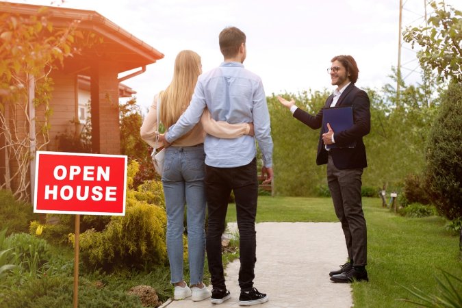 Real estate agent welcomes couple to open house.